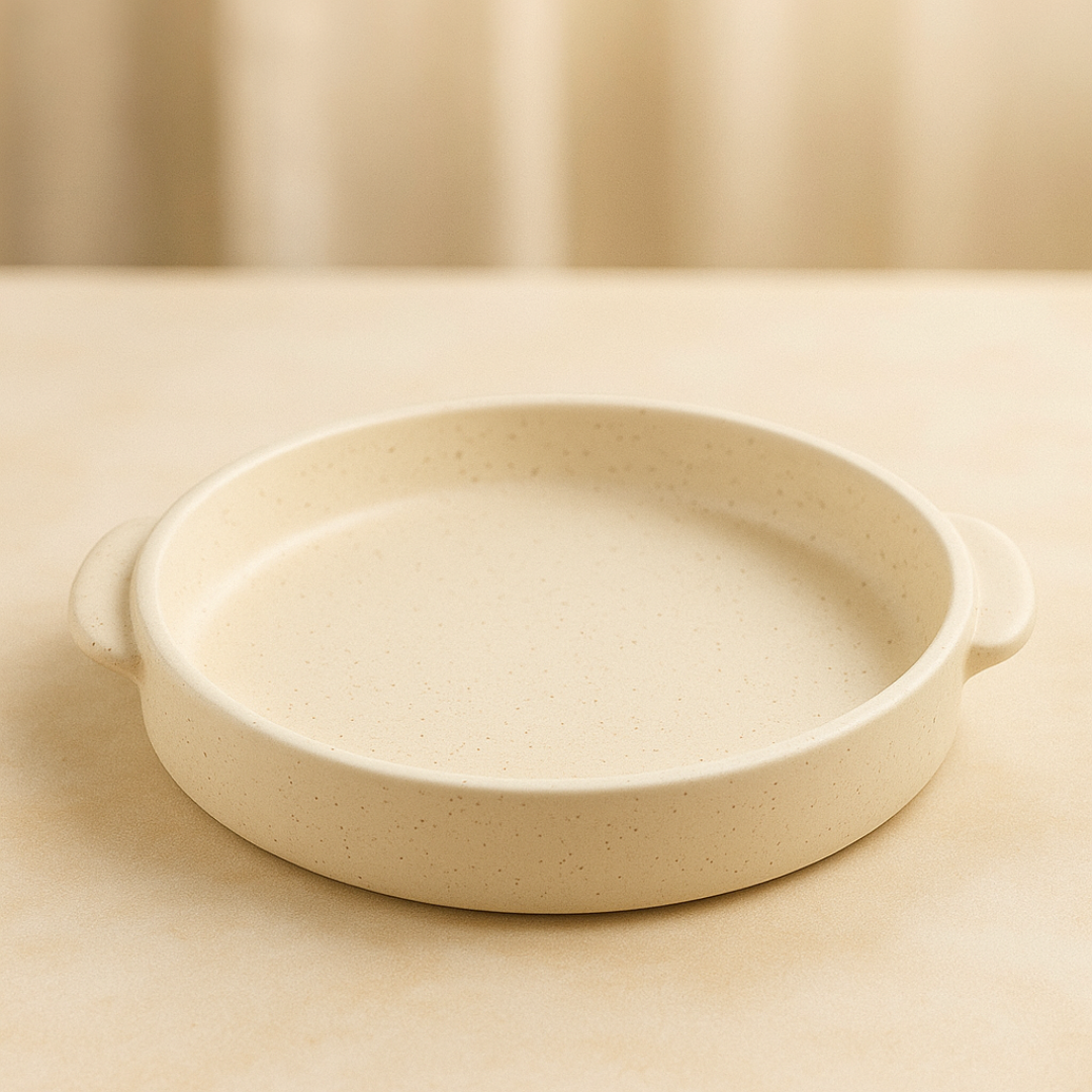 Round beige ceramic tray with side handles, matte speckled finish, minimalistic and elegant, shown on neutral-toned surface.