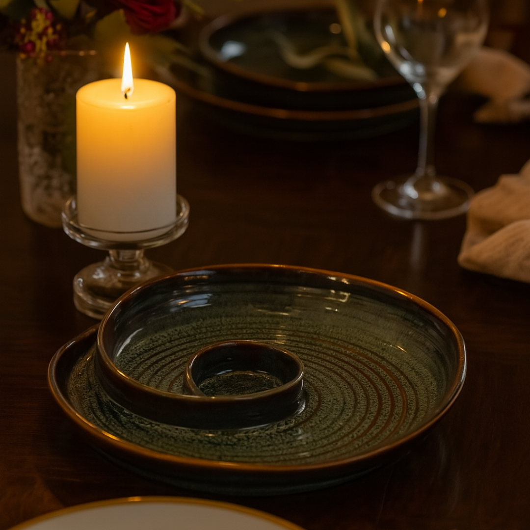 Moody dinner table with lit candle and IndoCasa ceramic platter in focus; wine glass and florals in background